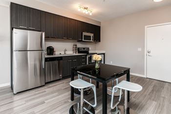 A kitchen with a black table and white chairs.